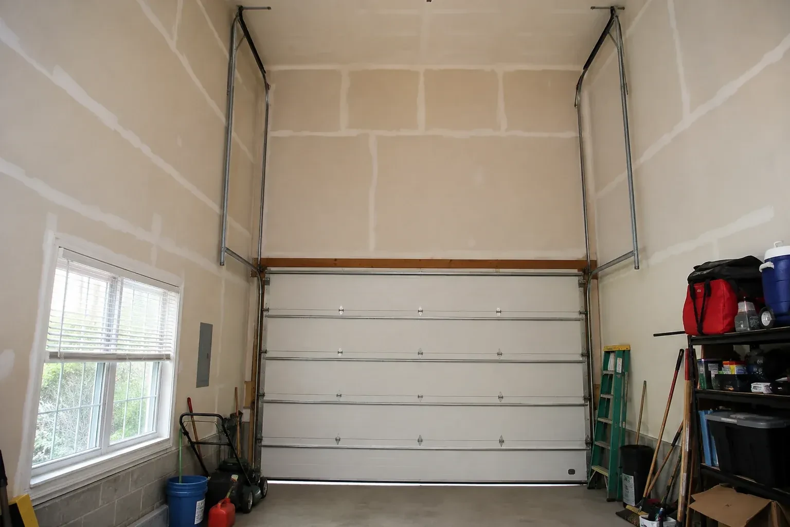 Tall garage interior with a sectional door and tracks extending into overhead space. — High-Lift Garage Door Conversion, London